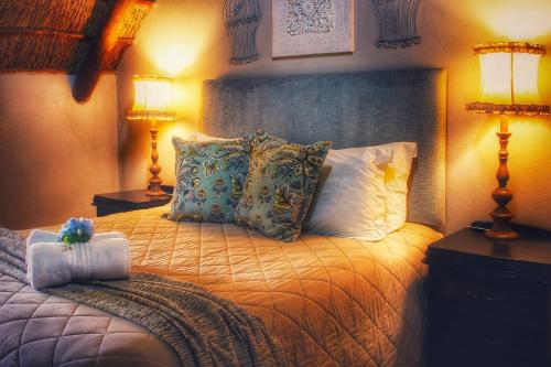 a bedroom with a bed with pillows and two lamps at Clivia Lodge in Vanderbijlpark