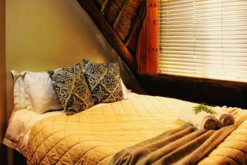 a bedroom with a bed with pillows and a window at Clivia Lodge in Vanderbijlpark