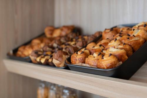 a shelf filled with different types of pastries on at Aparthotel 37 Lodge Courbevoie Paris La Défense in Courbevoie