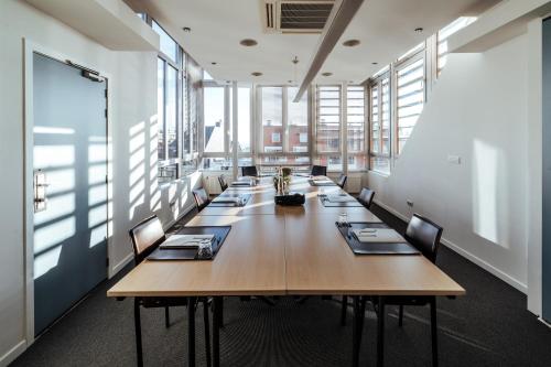 a long table in a large room with windows at Cosmopolite Hotel Nieuwpoort-Bad in Nieuwpoort