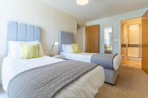 a hotel room with two beds and a bathroom at Cotels at Vizion Serviced Apartments, Superfast Broadband, Central Location, Free Parking, Fully Equipped Kitchen in Milton Keynes