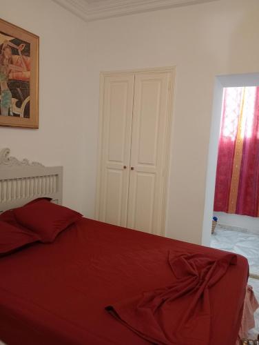 a bedroom with a red bed and a window at Mia casa in La Goulette