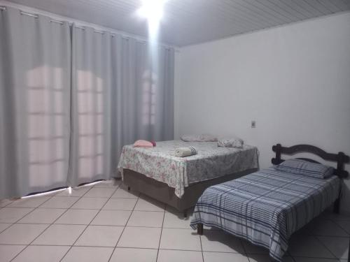 a bedroom with two beds and a window at Suits - Canto do sabia in Brotas