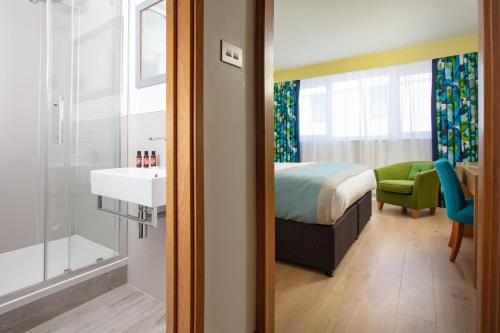 a bedroom with a bed and a bathroom with a sink at Bedruthan Hotel & Spa in Newquay
