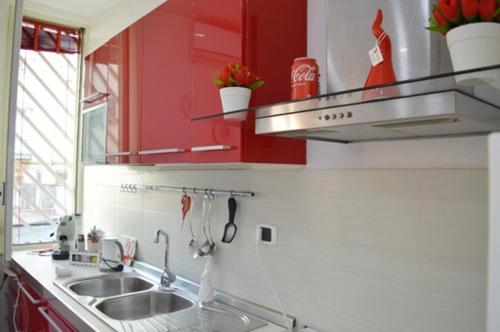 uma cozinha com armários vermelhos e um lavatório em “La Casa di Margi” em Nápoles