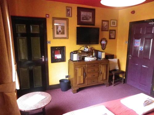 uma sala de estar com televisão e uma cómoda de madeira em Fifteens of Swinley em Wigan