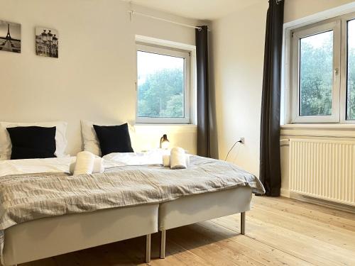 a bedroom with a large bed with two windows at One-Bedroom Apartment Located In The Charming City Of Odense, in Odense