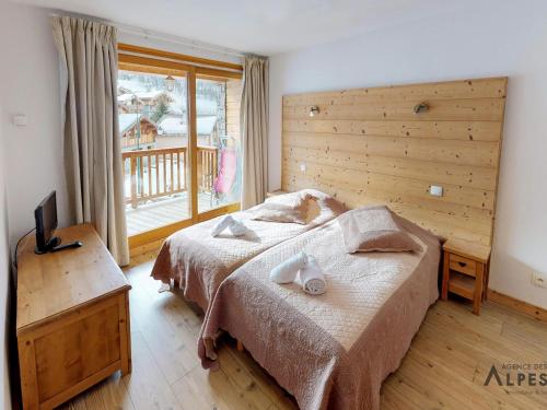 een slaapkamer met een bed en een groot raam bij Chalet haut de gamme 8 chambres avec sauna à 250m des pistes, St Martin de Belleville - FR-1-452-75 in Saint-Martin-de-Belleville