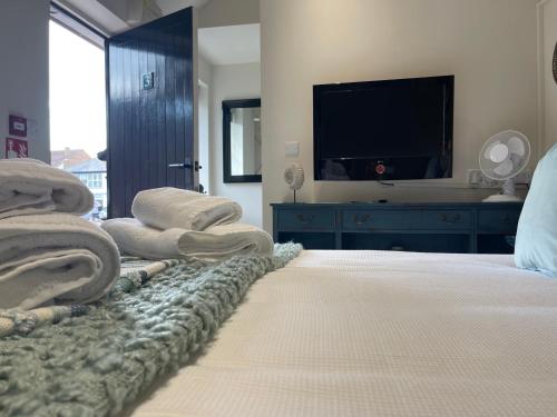 a bedroom with a bed with a flat screen tv at The Courtyard Rooms in Brightlingsea