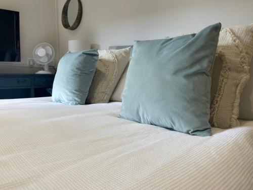 a bed with two blue pillows on top of it at The Courtyard Rooms in Brightlingsea