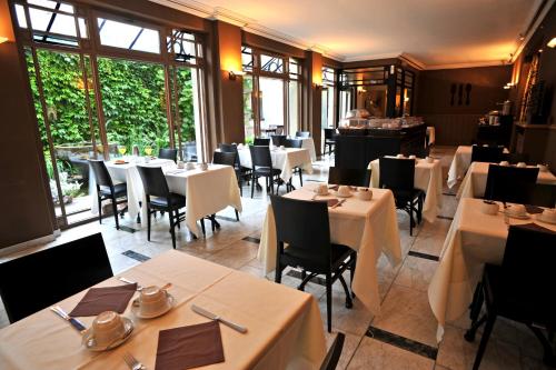 a restaurant with white tables and chairs and windows at Flanders Hotel in Bruges