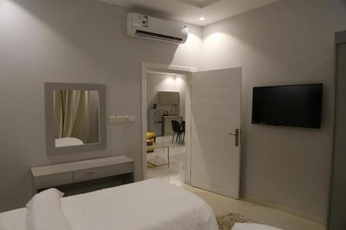 a white bedroom with a bed and a television at Areen Hotel Al Naeem in Jeddah