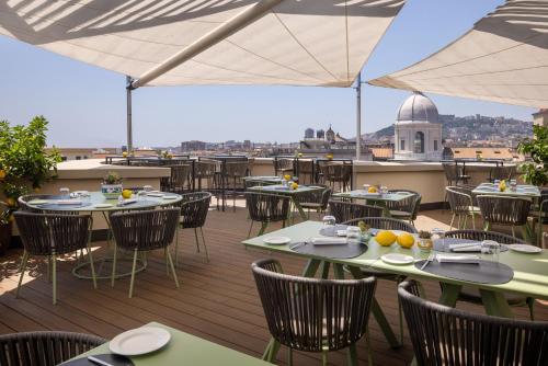 a restaurant with tables and chairs on a deck at UNAHOTELS Napoli in Naples
