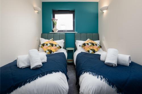 two beds in a room with blue walls at Modern 2 Bedroom Apartment with Parking by At Hem in Southampton
