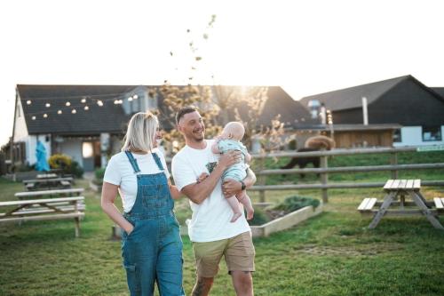 a man and woman holding a baby in a field at The Potting Barn in Saint Ervan