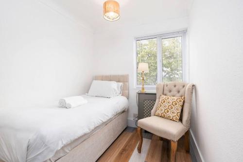um quarto com uma cama, uma cadeira e uma janela em 3 BR Chic Home with Balcony & Free Parking! em Leeds