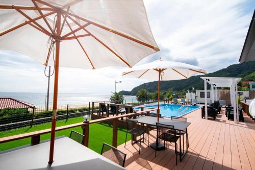 a patio with tables and umbrellas next to a pool at Setouchi Island Stays Suo Oshima in Suo Oshima