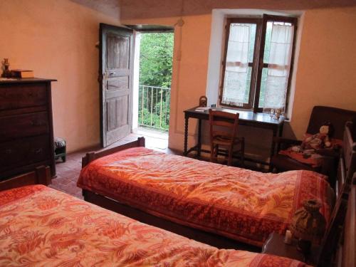 a bedroom with two beds and a desk and a window at Meiro di Choco in Pradleves