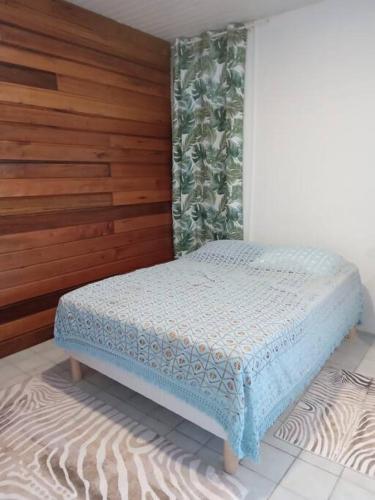 a small bed in a room with a wooden wall at Studio proche aéroport 2perswifi in Matoury