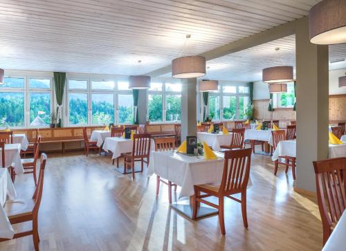 a restaurant with white tables and chairs and windows at JUFA Hotel Bad Aussee in Bad Aussee