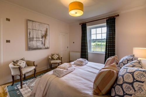 een slaapkamer met een bed en 2 stoelen en een raam bij Fairygreen Cottage in Perth