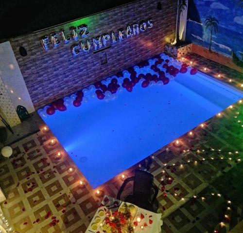 a swimming pool in front of a building with lights at Finca hotel casa rosada in Tuluá