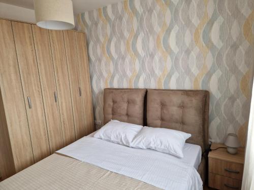 a bedroom with a bed with white sheets and a wall at VV apartman in Bijeljina