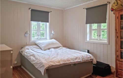 a bedroom with a bed and two windows at Cozy Home In Grimstad With House Sea View in Grimstad