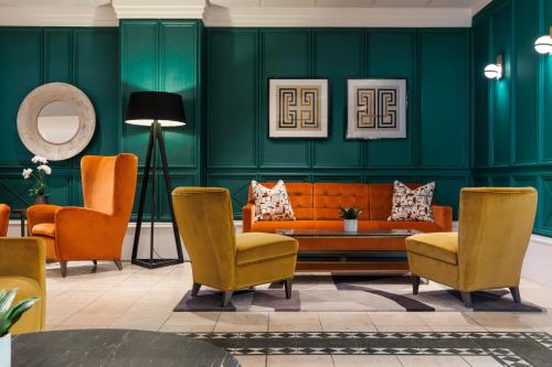 a living room with green walls and orange chairs at Crowne Plaza Leeds by IHG in Leeds