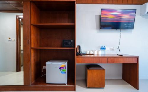 Cette chambre comprend un bureau et une télévision murale. dans l'établissement GP House Phuket Patong Beach, à Patong Beach
