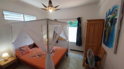 Schlafzimmer mit einem Bett und einem Deckenventilator in der Unterkunft CHEZ ALYSSA in Nosy Be