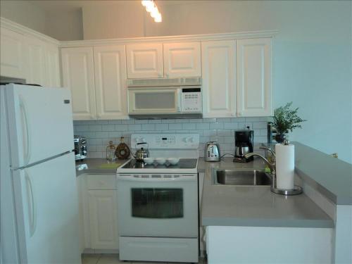cocina blanca con fregadero y nevera en Spacious One bedroom Bay View Penthouse, en Miami Beach