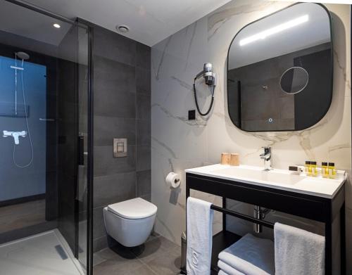 a bathroom with a sink and a toilet and a mirror at Sercotel Plana Suites in Vall de Uixó