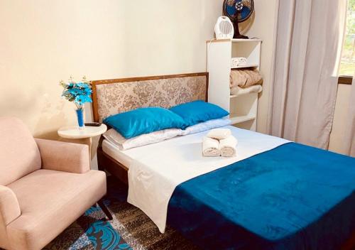a bedroom with a bed with blue pillows and a chair at Residenciais Maria Flor in Gramado