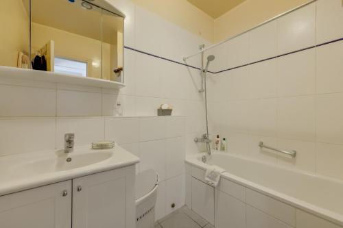 un bagno bianco con lavandino e vasca di Charmant 53m² avec balcon à Neuilly-sur-Seine a Neuilly-sur-Seine