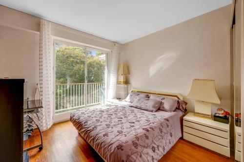 una camera con un letto e una grande finestra di Charmant 53m² avec balcon à Neuilly-sur-Seine a Neuilly-sur-Seine