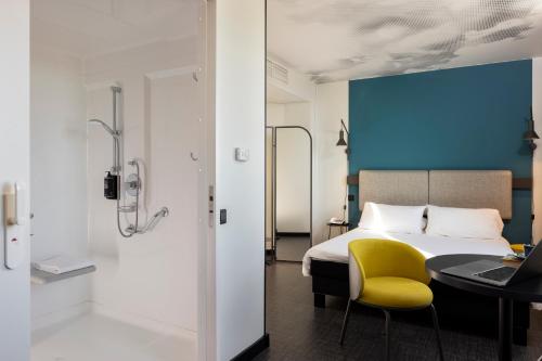 a bedroom with a bed and a table and a yellow chair at ibis Marseille Centre Euromed in Marseille