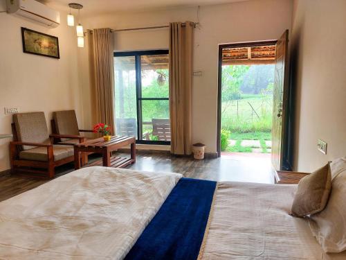 a bedroom with a bed and a table and a window at Grand Narmada Homestay Resort-Bandhavgarh in Tāla