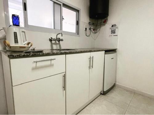 eine Küche mit weißen Schränken, einer Spüle und einem Kühlschrank in der Unterkunft Alojamiento Don Miguel 