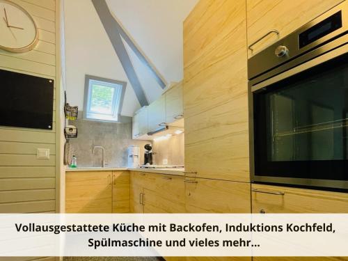 uma cozinha com armários de madeira e um micro-ondas em Mein-Seepark, Ferienhaus Heike em Kirchheim