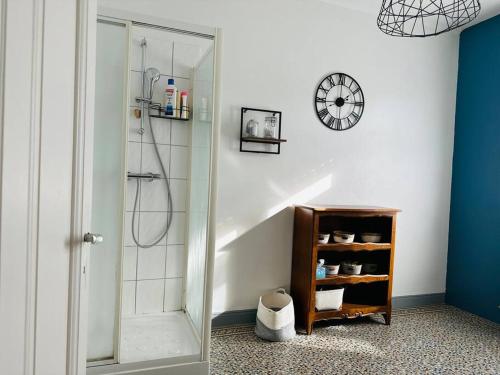 a bathroom with a shower and a clock on the wall at Cottage Arlette à 600m de la mer in Cayeux-sur-Mer