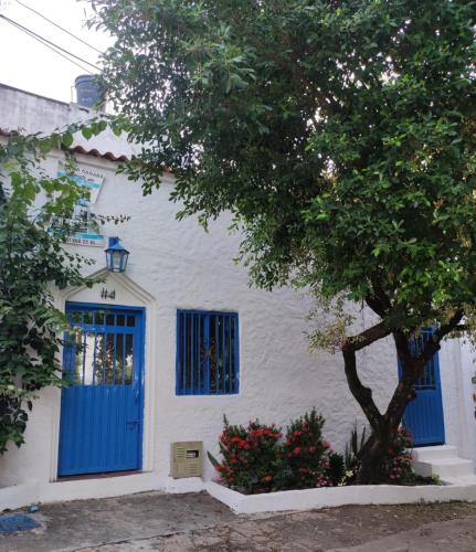 a white house with blue doors and a tree at Cabaña 41, aldea Doradal Santorini Colombiano in Puerto Triunfo