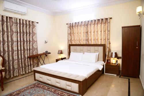 a bedroom with a large bed and curtains at Waypoint Hotel in Karachi