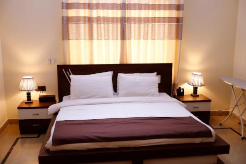 a bedroom with a large bed with two lamps at Waypoint Hotel in Karachi