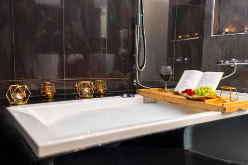 a bath tub with a plate of fruit and a glass of wine at Komorowski Luxury Guest Rooms in Kraków
