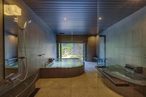 een grote badkamer met een bad en een douche bij Ureshino Yadoya in Ureshino