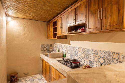 a kitchen with wooden cabinets and a stove top oven at Uma Sri Dewi Villa Ubud in Ubud