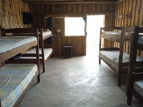 a room with several bunk beds and a window at Vida Playera in Punta Del Diablo