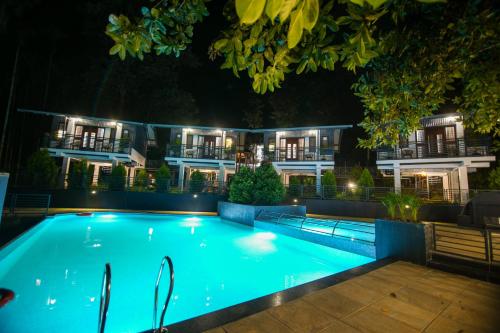 a swimming pool in front of a building at night at B'camp Resorts & Homestays in Wayanad
