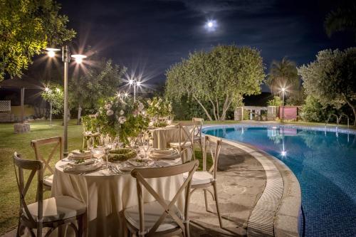 a table set up for a wedding by a pool at night at Cruccùris Resort - Adults Only in Villasimius